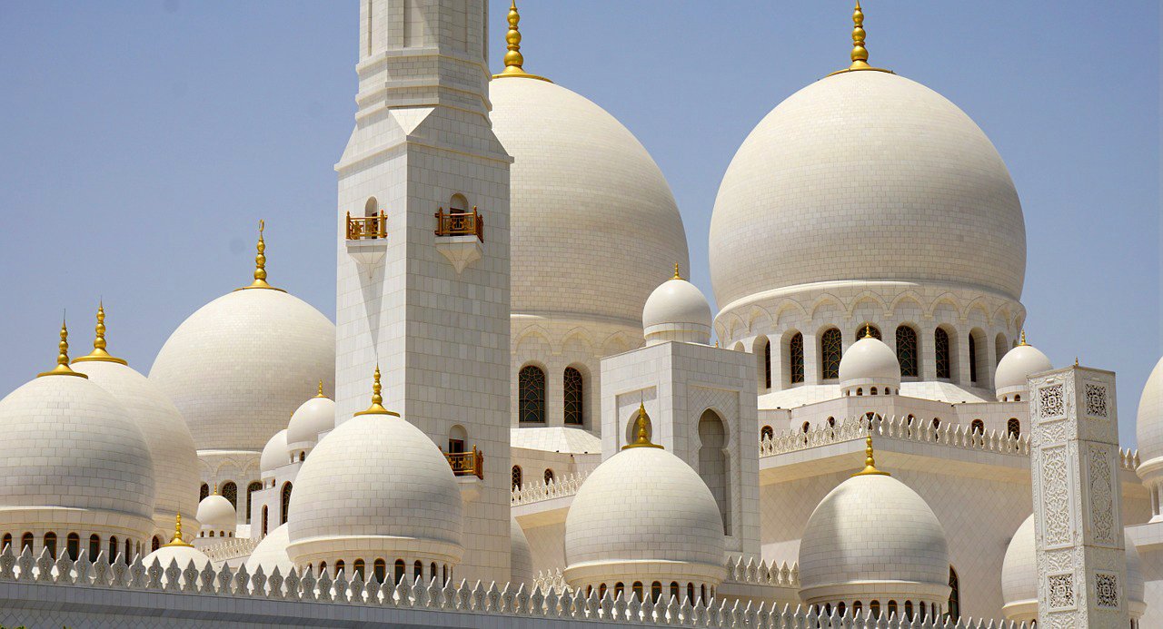 Sheikh Zayed Grand Mosque domes and minarets in Abu Dhabi, UAE, under a clear blue sky.