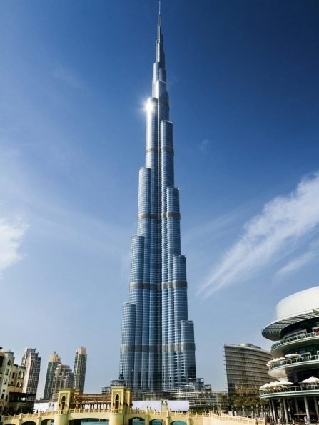Burj Khalifa, the world's tallest building, in Dubai, United Arab Emirates, with a clear blue sky and water in the foreground.